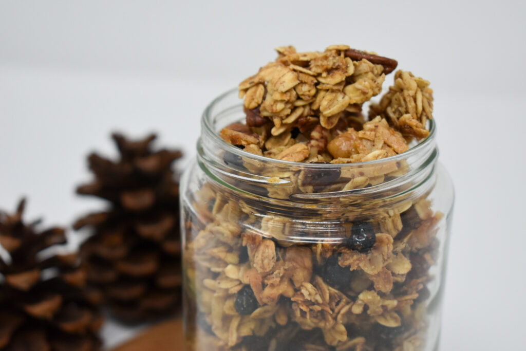 close-up of granola in jar with pinecones in bakground