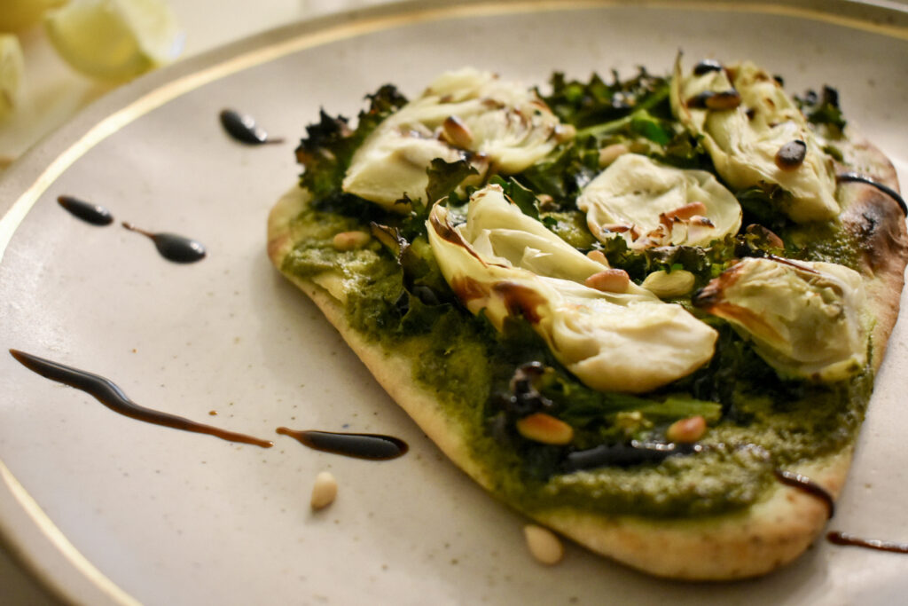 close up of artichoke and pesto pizza on gray plate