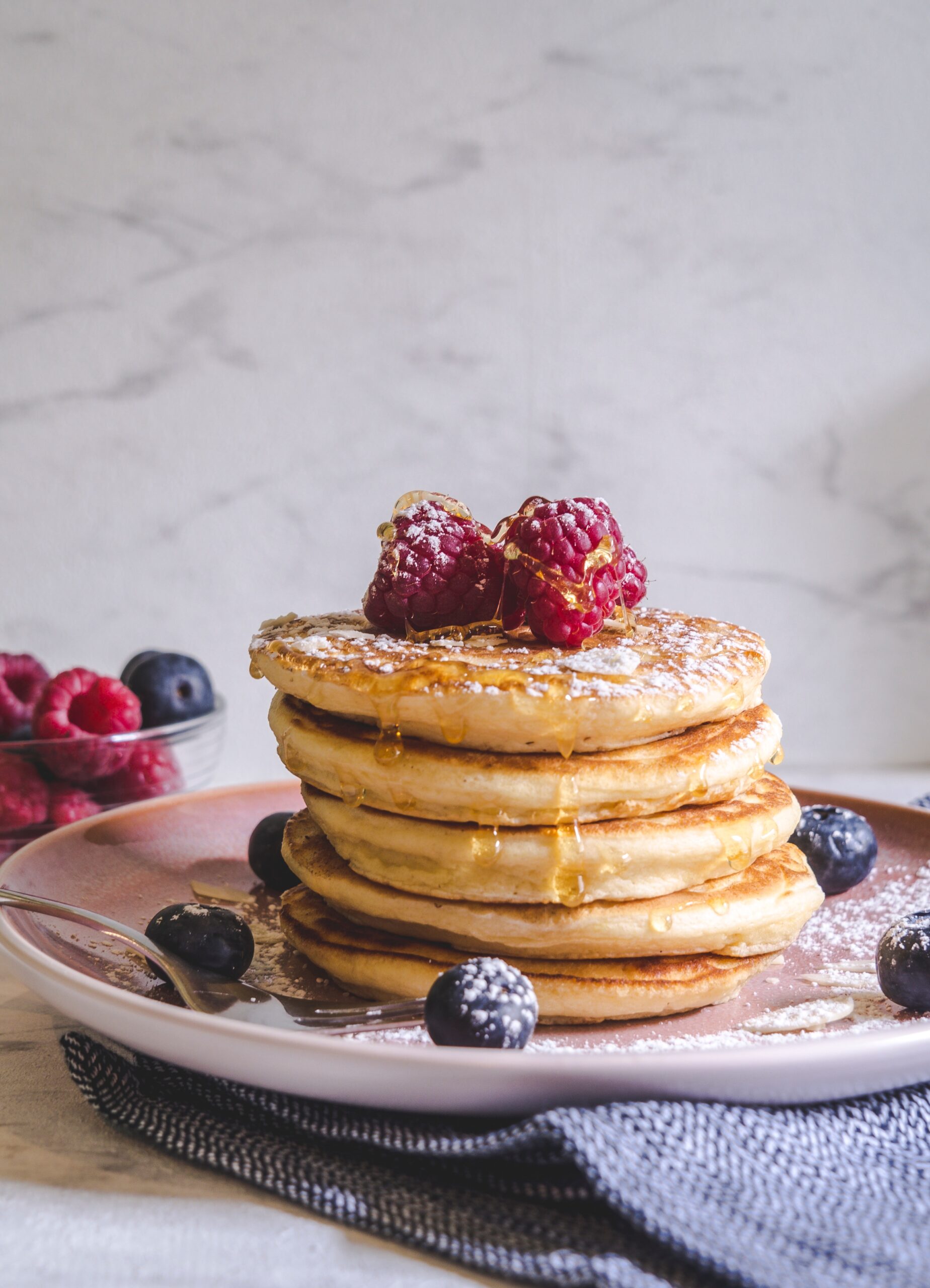 stack of pancakes with raspberries and blueberries on top